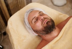 young bearded handsome man lying on the massage table at beauty salon ready to receive spa treatment and beauty therapy